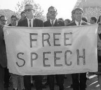 Men holding up a banner saying "Free Speech"